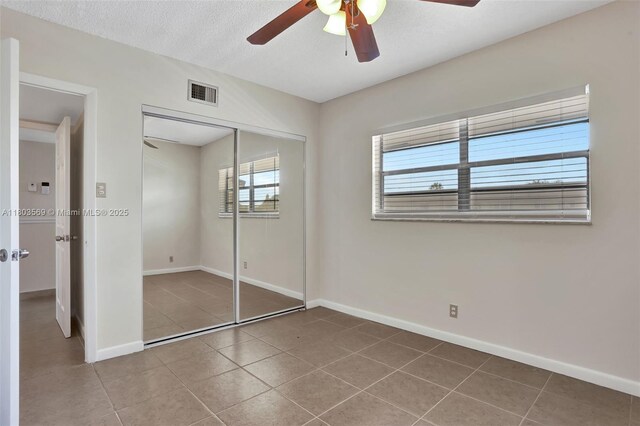 551 NW 80th Ter Unit 203, Margate, FL 33063 - unfurnished bedroom with tile patterned flooring, baseboards, a closet, a ceiling fan, and a textured ceiling