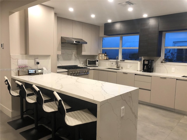 9224 Byron Ave, Surfside, FL 33154 - kitchen with gas stove, a sink, modern cabinets, under cabinet range hood, and light stone counters