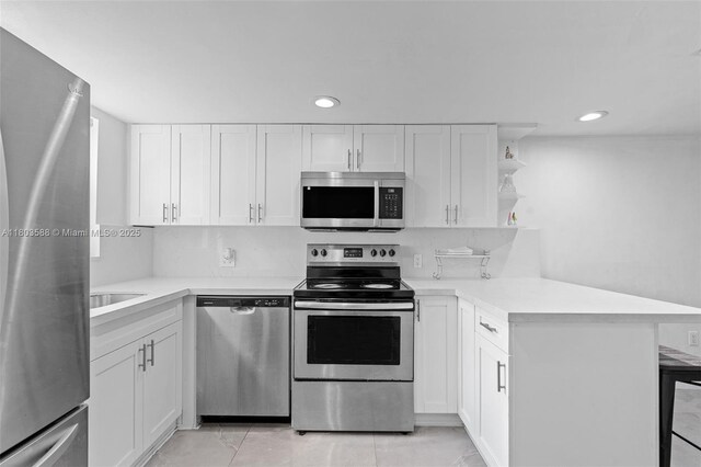 5530 W 26th Ct Unit 209, Hialeah, FL 33016 - kitchen featuring appliances with stainless steel finishes, a peninsula, light countertops, white cabinetry, and recessed lighting
