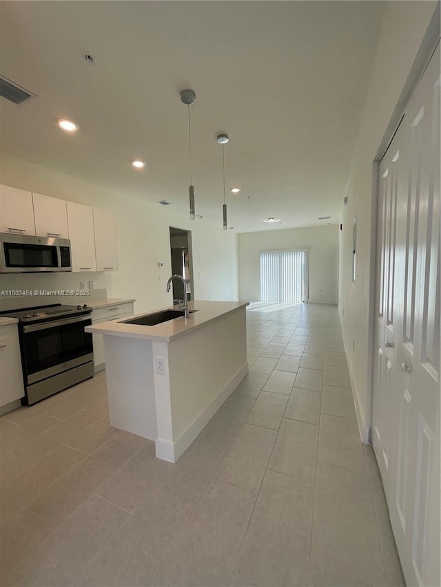 kitchen featuring appliances with stainless steel finishes, a sink, light tile patterned floors, open floor plan, and white cabinetry