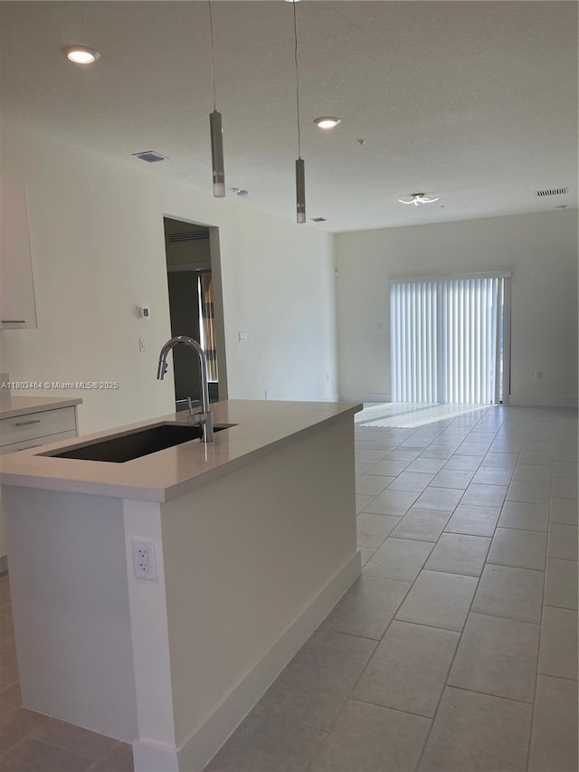 kitchen with a sink, open floor plan, a center island with sink, light countertops, and light tile patterned flooring