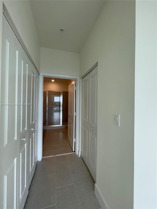 corridor with tile patterned flooring and baseboards