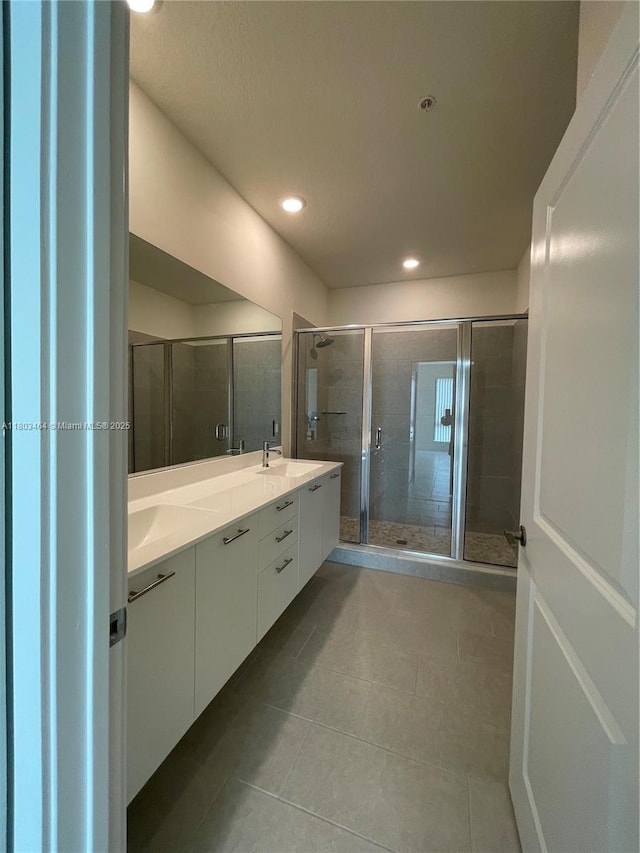 bathroom featuring tile patterned floors, a stall shower, double vanity, and recessed lighting