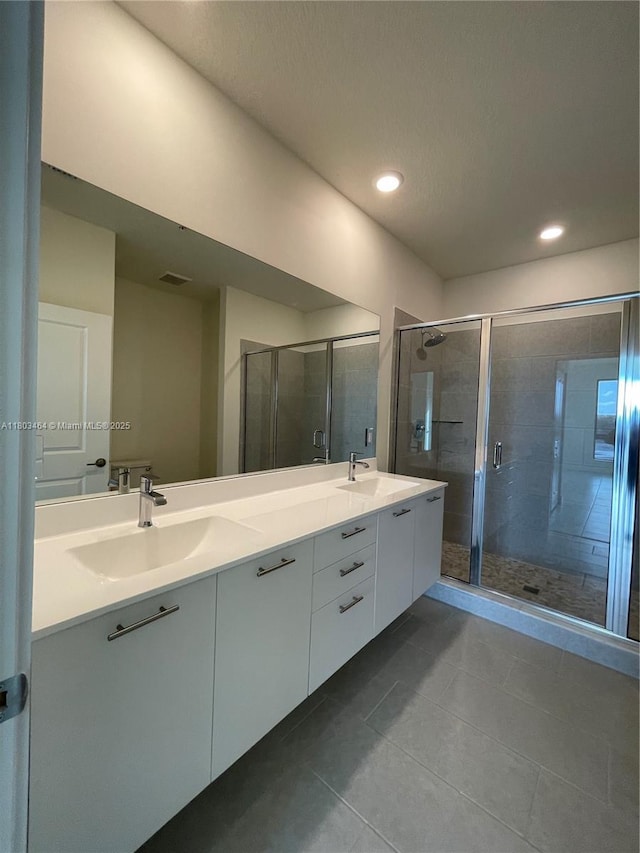 bathroom featuring tile patterned flooring, a shower stall, double vanity, and recessed lighting