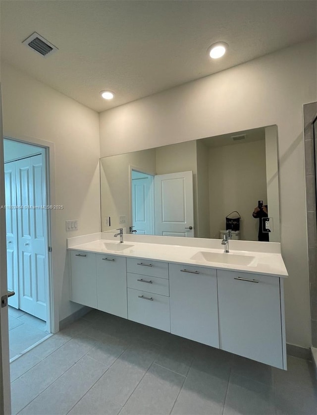bathroom featuring double vanity, tile patterned floors, baseboards, and recessed lighting