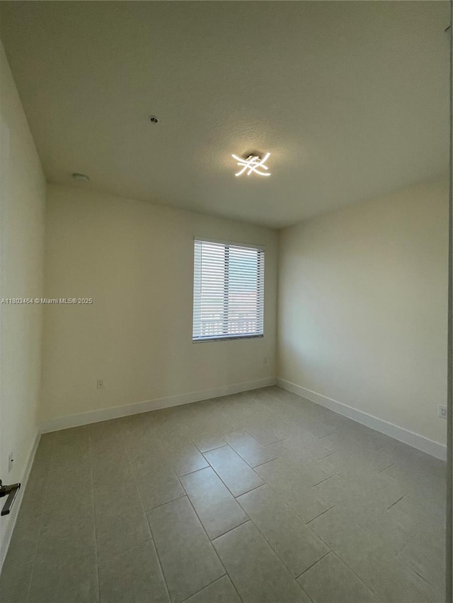 spare room with tile patterned flooring and baseboards