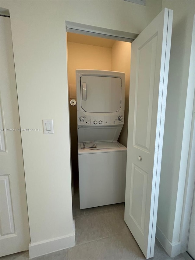 washroom featuring stacked washer / dryer and light tile patterned floors