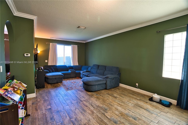 living room featuring crown molding, hardwood / wood-style floors, baseboards, arched walkways, and a textured ceiling