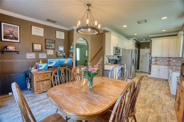dining room with arched walkways, light wood-type flooring, a chandelier, crown molding, and stairs