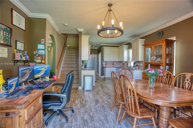 dining area with light wood-style floors, a chandelier, ornamental molding, stairway, and a textured ceiling