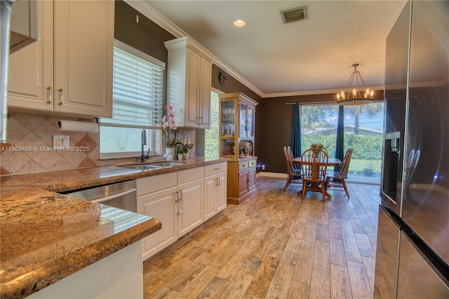 kitchen with a sink, stainless steel appliances, a chandelier, light wood-type flooring, and crown molding