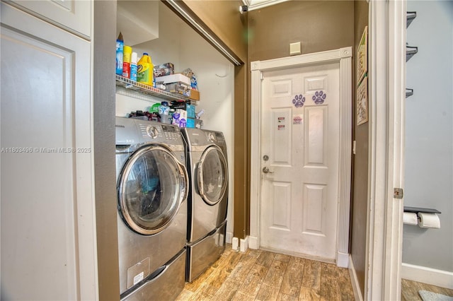 clothes washing area with washing machine and clothes dryer, light wood-type flooring, and baseboards