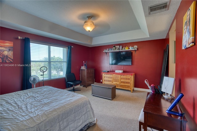 carpeted bedroom featuring a tray ceiling and baseboards