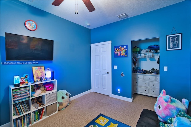 recreation room with carpet floors, a ceiling fan, baseboards, and a textured ceiling