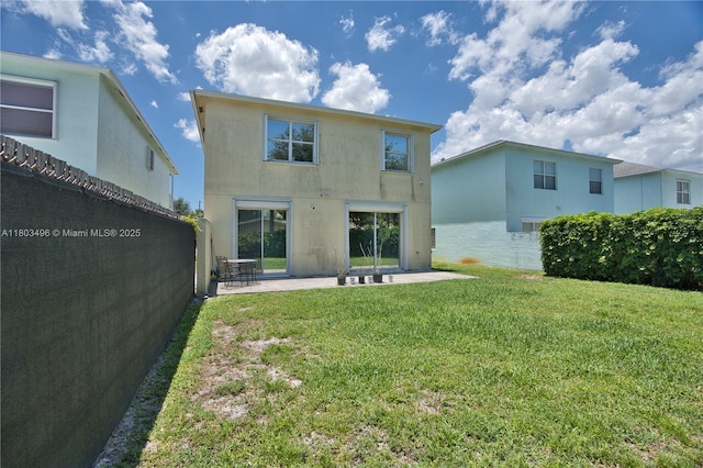 rear view of house with a patio, a lawn, and stucco siding