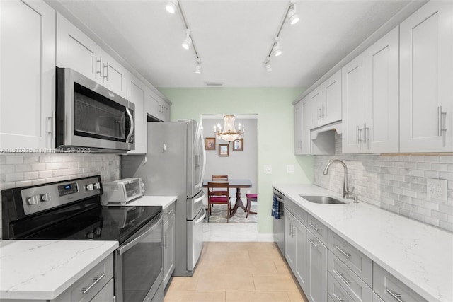 1897 SW 20th Cir, Boynton Beach, FL 33426 - kitchen featuring appliances with stainless steel finishes, a chandelier, decorative backsplash, light tile patterned floors, and light stone counters