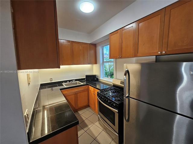 900 16th St Unit 207, Miami Beach, FL 33139 - kitchen with stainless steel appliances, a sink, brown cabinets, light tile patterned flooring, and dark countertops