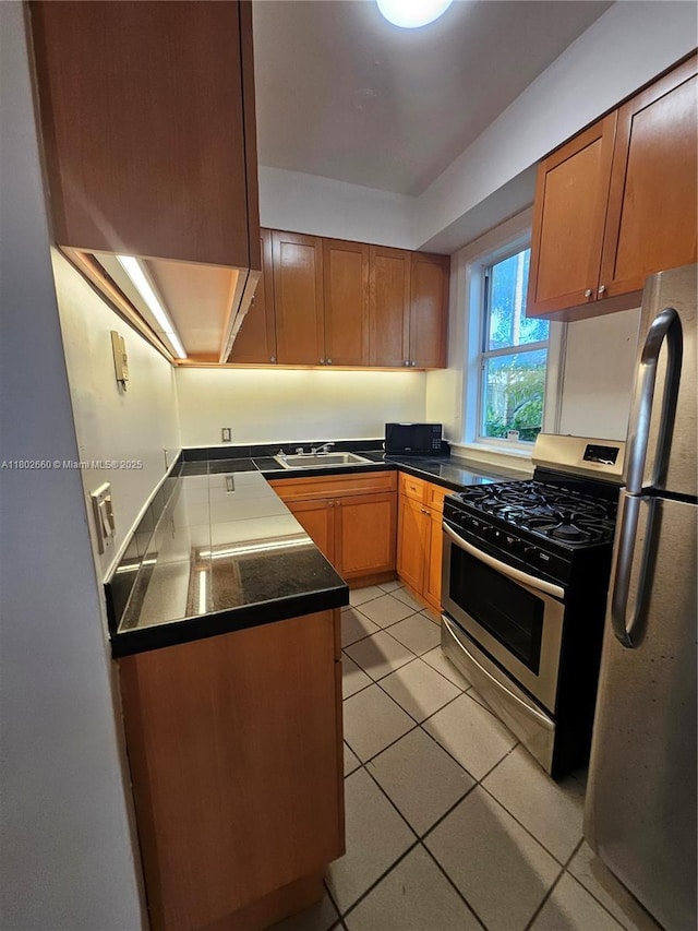 900 16th St Unit 207, Miami Beach, FL 33139 - kitchen featuring stainless steel appliances, a sink, light tile patterned floors, dark countertops, and brown cabinetry