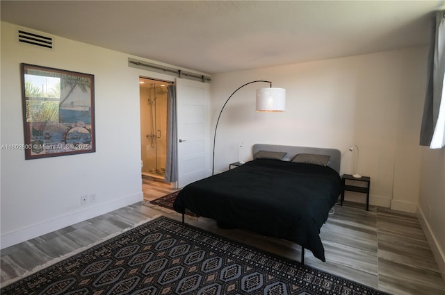 401 SE 3rd St Unit 403, Dania Beach, FL 33004 - bedroom with wood finished floors, baseboards, connected bathroom, and a barn door