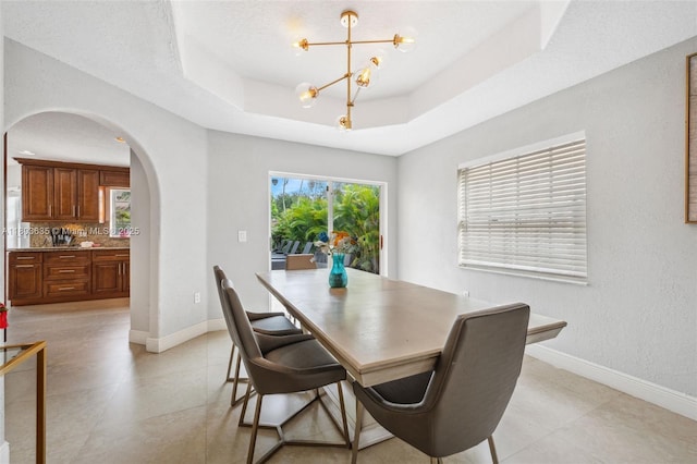 2238 NW 139th Ave, Sunrise, FL 33323 - dining room featuring arched walkways, a chandelier, baseboards, a raised ceiling, and light tile patterned floors