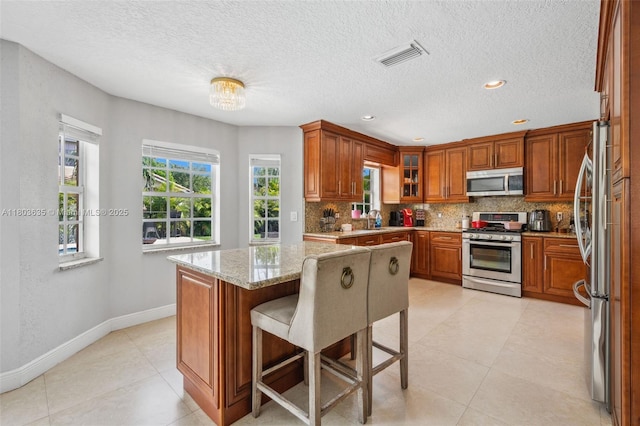 2238 NW 139th Ave, Sunrise, FL 33323 - kitchen with stainless steel appliances, decorative backsplash, a sink, brown cabinetry, and baseboards