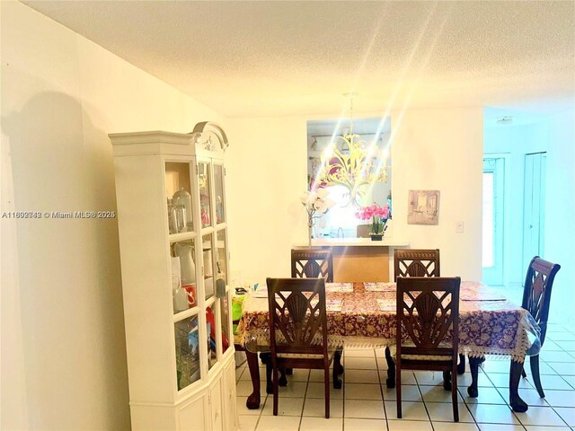 dining room with a textured ceiling, a chandelier, and light tile patterned floors