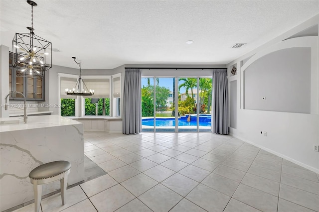 12339 NW 25th St, Coral Springs, FL 33065 - unfurnished living room featuring a chandelier, light tile patterned floors, a textured ceiling, a sink, and baseboards