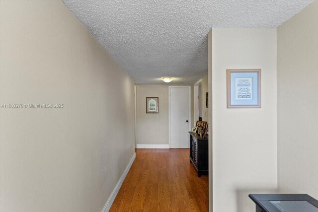 9750 SW 143rd Dr, Miami, FL 33176 - corridor featuring a textured ceiling, wood finished floors, and baseboards