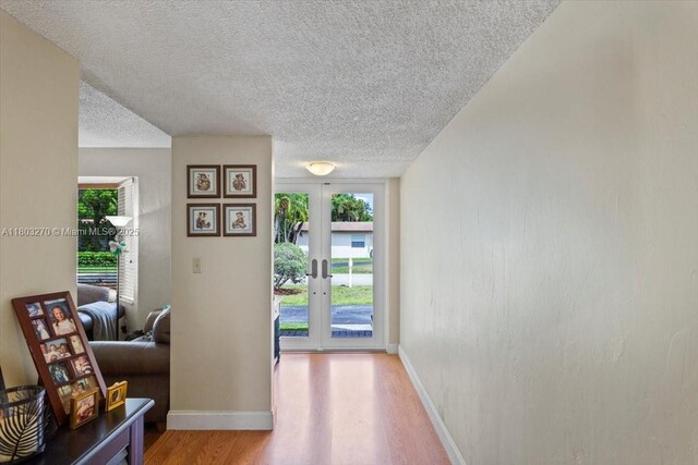 9750 SW 143rd Dr, Miami, FL 33176 - hallway with light wood-style flooring, baseboards, a textured ceiling, and french doors