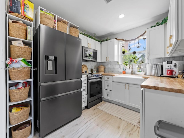 7165 W 13th Ave, Hialeah, FL 33014 - kitchen with stainless steel appliances, a sink, wooden counters, white cabinetry, and tasteful backsplash