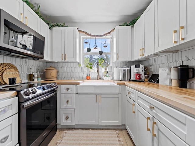 7165 W 13th Ave, Hialeah, FL 33014 - kitchen with appliances with stainless steel finishes, wooden counters, a sink, tasteful backsplash, and white cabinetry