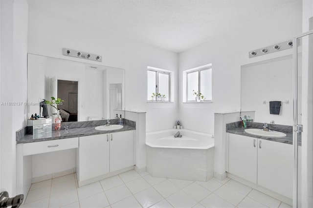 2350 SE 19th Ct Unit 0, Homestead, FL 33035 - ensuite bathroom with two vanities, a garden tub, a textured ceiling, and tile patterned flooring