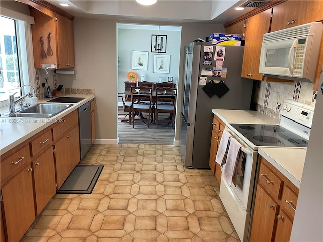 1101 SW 75th Ter, Plantation, FL 33317 - kitchen featuring appliances with stainless steel finishes, light countertops, decorative backsplash, brown cabinetry, and a tray ceiling