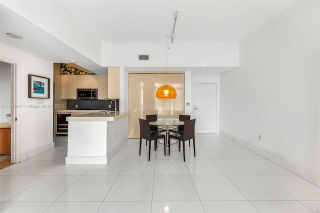 1155 Brickell Bay Dr Unit Ph204, Miami, FL 33131 - kitchen with stainless steel microwave, a peninsula, light countertops, beverage cooler, and decorative light fixtures