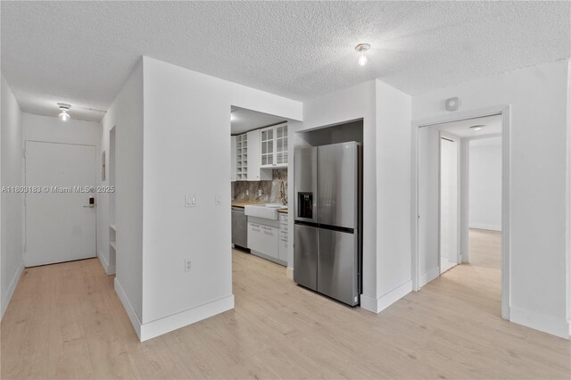 6886 N Kendall Dr Unit D207, Pinecrest, FL 33156 - kitchen featuring stainless steel appliances, light wood-style flooring, tasteful backsplash, a textured ceiling, and glass insert cabinets