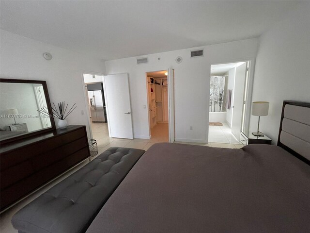 31 SE 6th St Unit 907, Miami, FL 33131 - bedroom with light tile patterned floors, stainless steel fridge, ensuite bath, and a walk in closet