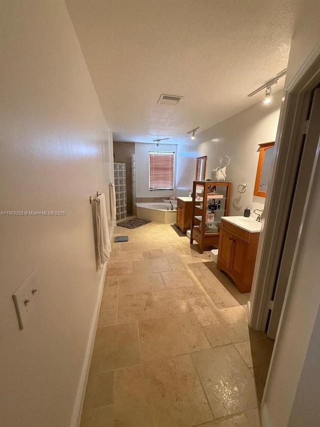 9740 SW 155th Ave, Miami, FL 33196 - bathroom with a textured ceiling, a bath, vanity, stone tile flooring, and baseboards