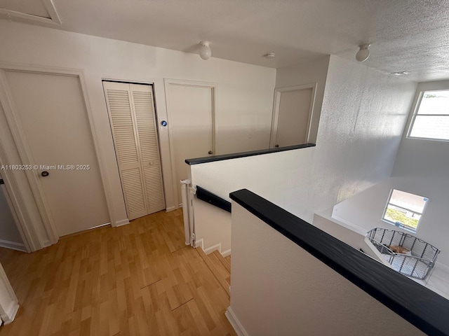 9740 SW 155th Ave, Miami, FL 33196 - corridor featuring an upstairs landing, light wood finished floors, a textured ceiling, and baseboards
