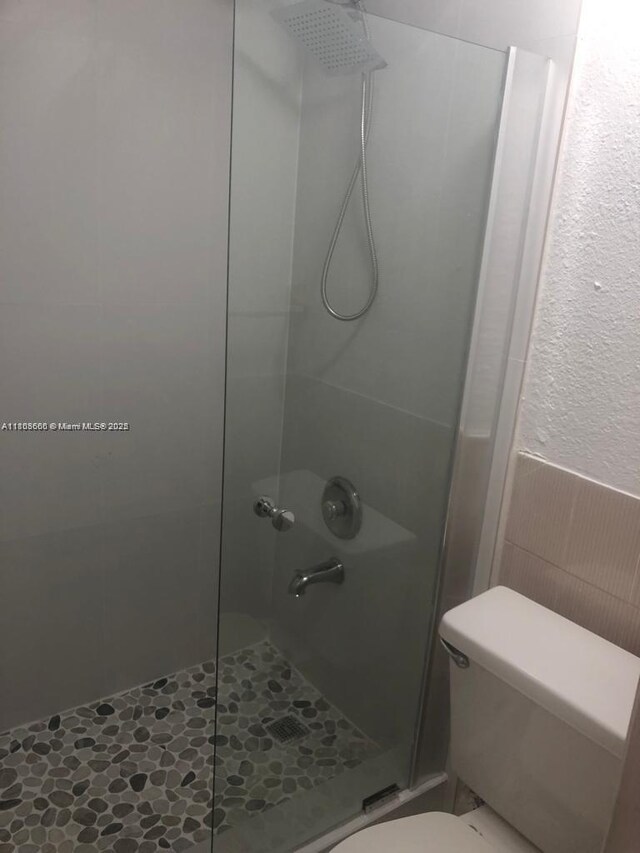 250 180th Dr Unit 108, Sunny Isles Beach, FL 33160 - full bathroom with toilet, a stall shower, wainscoting, and tile walls