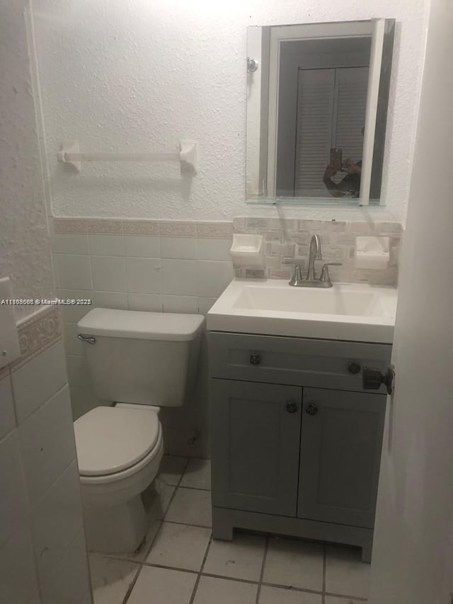 250 180th Dr Unit 108, Sunny Isles Beach, FL 33160 - bathroom with vanity, toilet, tile walls, a wainscoted wall, and a textured wall