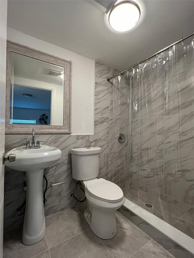 1472 NE 150th St, Miami, FL 33161 - bathroom featuring tiled shower, toilet, tile walls, and tile patterned floors