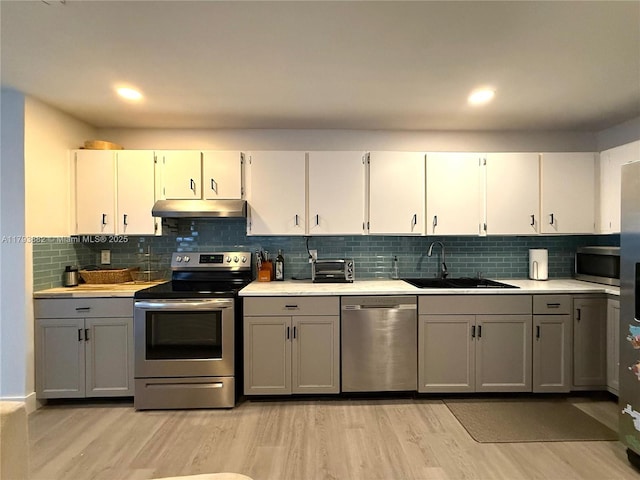 513 Racquet Club Rd Unit 56, Weston, FL 33326 - kitchen with appliances with stainless steel finishes, under cabinet range hood, light countertops, light wood finished floors, and gray cabinets