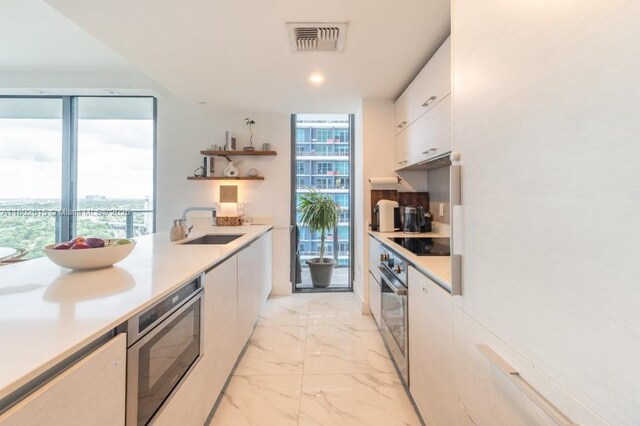 1300 S Miami Ave Unit 2006, Miami, FL 33130 - kitchen featuring open shelves, appliances with stainless steel finishes, a sink, white cabinetry, and light countertops