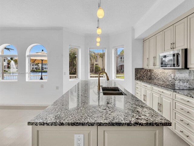 3144 NE 212th St, Aventura, FL 33180 - kitchen with stainless steel microwave, a sink, dark stone counters, a center island with sink, and tasteful backsplash