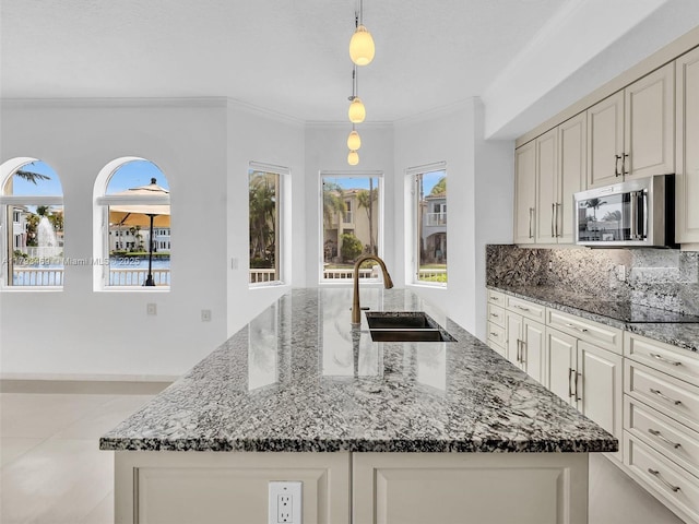 3144 NE 212th St, Aventura, FL 33180 - kitchen with stainless steel microwave, dark stone countertops, an island with sink, ornamental molding, and hanging light fixtures