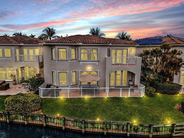 3144 NE 212th St, Aventura, FL 33180 - back of property at dusk with a balcony, a tiled roof, and stucco siding