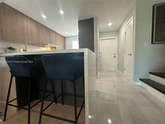 8443 SW 137th Ave Unit 8443, Miami, FL 33183 - kitchen featuring a kitchen breakfast bar, modern cabinets, baseboards, light countertops, and brown cabinetry