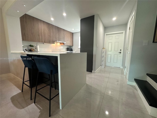 8443 SW 137th Ave Unit 8443, Miami, FL 33183 - kitchen with modern cabinets, a kitchen bar, brown cabinetry, light countertops, and a peninsula