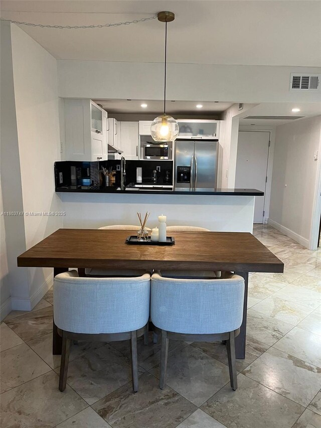 2301 Collins Ave Unit 731, Miami Beach, FL 33139 - kitchen with appliances with stainless steel finishes, baseboards, dark countertops, white cabinetry, and a peninsula