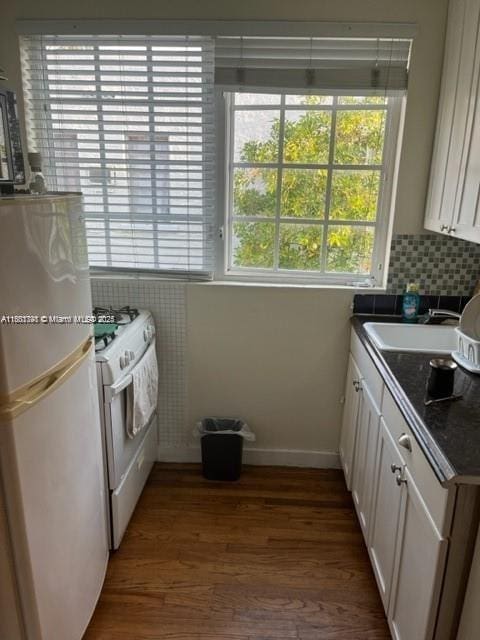 741 15th St Unit 8, Miami Beach, FL 33139 - kitchen with white appliances, a sink, dark countertops, wood finished floors, and white cabinetry
